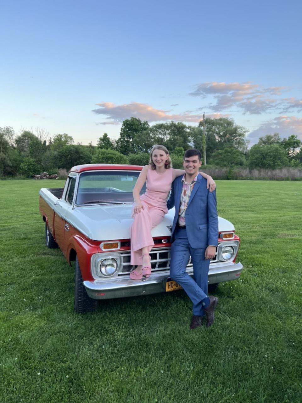 emily and clay sitting on an old truck